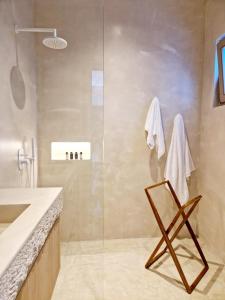 a bathroom with a glass shower and a chair at Ivy's Natural Resort in Arnados
