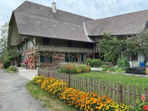 una casa con una valla y flores delante de ella en Schöne Ferienwohnung mit Hotpot und Sauna en Sumiswald