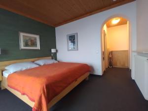 ein Schlafzimmer mit einem großen Bett mit einer orangefarbenen Decke in der Unterkunft Seeblick-Appartements Ossiach in Ossiach