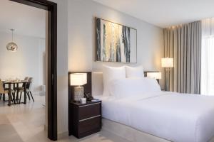 a bedroom with a large white bed and a table at Somerset Downtown Al Khobar in Al Khobar
