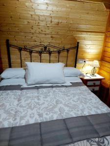 1 dormitorio con 1 cama y pared de madera en Cabañas los Pinos Arroyo Frio, en Arroyo Frío