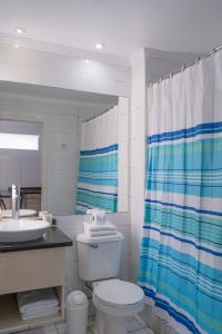 a bathroom with a toilet and a sink and a shower curtain at Apart Hotel Colors in La Serena