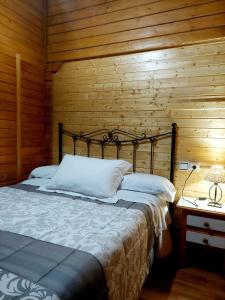 1 dormitorio con 1 cama y pared de madera en Cabañas los Pinos Arroyo Frio, en Arroyo Frío