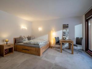 a bedroom with a bed and a table and a desk at Appartement Alpenlöwe in Kirchberg in Tirol