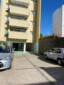 two cars parked in a parking lot in front of a building at Departamentos de Categoría, Santa Fé y Alberti in Mar del Plata