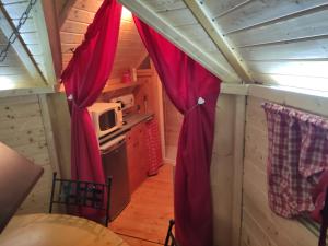 a kitchen with red curtains in a tiny house at Au Doubs Kota in Montlebon +23 photos