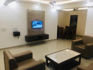 a living room with a couch and a tv on the wall at Vaishnavi furnished flats in Mangalore
