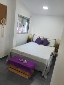 a bedroom with a bed with purple sheets and a window at Casa acogedora y funcional in Atlántida