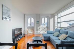 uma sala de estar com um sofá azul e uma televisão em Céntrico Ático frente al Mar em Vigo