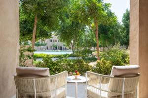une terrasse avec 2 chaises, une table et des arbres dans l'établissement Zulal Wellness Resort by Chiva-Som, à Ar Ruʼays