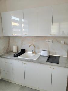 a kitchen with white cabinets and a sink at Oaza apartmani 1 in Senta