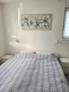 a bed in a bedroom with a painting on the wall at Oaza apartmani 1 in Senta