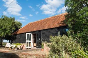 a black cottage with a red roof and white doors at Bromans Barn a beautiful cottage by the Sea and Cudmore Nature Reserve in West Mersea
