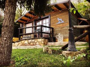 una baita di tronchi con un portico e un albero di Cabañas De Madera Y Bungalows - Gilmañas 3 a La Iruela