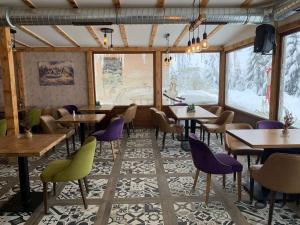 Un comedor con mesas y sillas y ventanas. en Popović apartmani, Sunčani breg, en Kopaonik