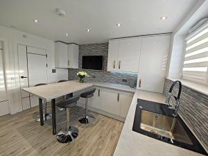 a kitchen with white cabinets and a table with stools at Private Room in Exclusive Apartment in Aberdeen