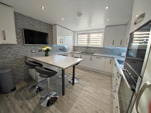 a kitchen with a table and a tv on the wall at Private Room in Exclusive Apartment in Aberdeen