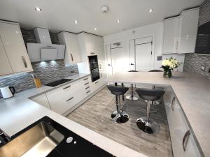 Private Room in Exclusive Apartment في أبردين: مطبخ مع دواليب بيضاء وجزيرة مطبخ مع الكراسي