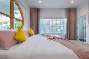 - une chambre avec un grand lit blanc et des oreillers jaunes dans l'établissement Ther house Banchang, à Ban Chang