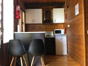 a kitchen with two black chairs and a counter at Cabañas De Madera Y Bungalows - Gilmañas 3 in La Iruela