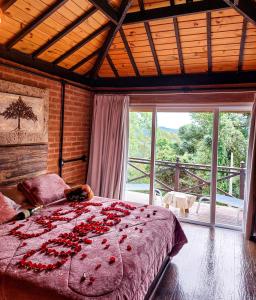 Chalés Descanso na Serra في مونتي فيردي: غرفة نوم عليها سرير وورد احمر
