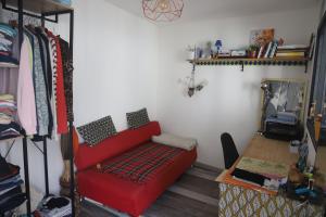 uma sala de estar com um sofá vermelho e uma prateleira em Loft Saint-Denis/Porte de Paris em Saint-Denis