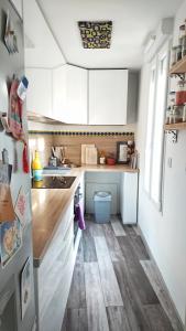 una pequeña cocina con armarios blancos y suelo de madera. en Loft Saint-Denis/Porte de Paris, en Saint-Denis