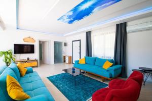 sala de estar con sofá azul y sillas rojas en Dreamy Villa with Private Pool and Jacuzzi in Kas, en Sarıbelen