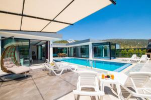 una casa con piscina y sillas blancas en Dreamy Villa with Private Pool and Jacuzzi in Kas, en Sarıbelen