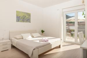 a white bedroom with a bed and a window at Apartments Olive Tree in Hvar