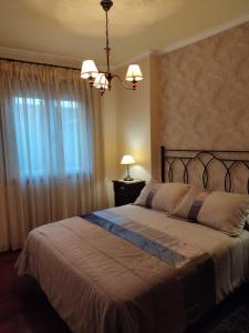 - une chambre avec un grand lit et un lustre dans l'établissement Apartamento La Real, à Caldas de Reis