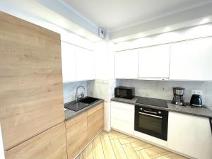 a small kitchen with white cabinets and a sink at Apartament Superior Blue Przy Plaży in Kołobrzeg