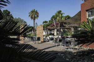 un patio con sedie, tavoli e palme di Belambra Clubs Borgo - Pineto a Borgo