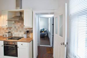 a kitchen with white cabinets and a view of a living room at Host & Stay - Windsor Cottage in Saltburn-by-the-Sea