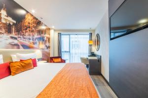a bedroom with a large white bed and a desk at Hotel Indigo Madrid - Gran Vía by IHG in Madrid
