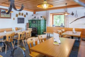 a restaurant with wooden tables and chairs and a fireplace at Berggasthof Hörnerhaus in Bolsterlang