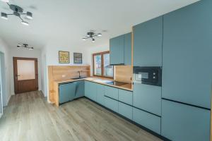 a large kitchen with blue cabinets and a wooden floor at CasiAna Apartment in Râşnov