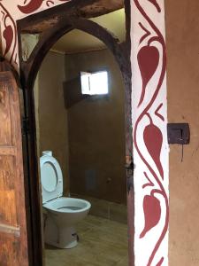 a bathroom with a toilet and a door open at Sahara Authentic Berber Camp in Mhamid