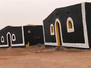 a black and white building with windows in the desert at Sahara Authentic Berber Camp in Mhamid