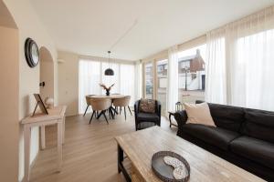 een woonkamer met een zwarte bank en een tafel bij Blankebil Studios & Apartments in Zandvoort