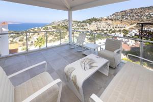 a balcony with white furniture and a view of the ocean at Amazing Duplex House with Sea View in Bodrum in Gumusluk