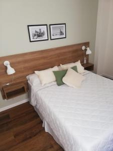 1 dormitorio con 1 cama blanca grande y 2 lámparas en departamentos del mar-Solo familias en Mar del Plata