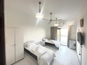 Low Priced New Residential Rooms for rent in Dubai near DAFZA Metro Station في دبي: غرفة نوم بسريرين وتلفزيون فيها
