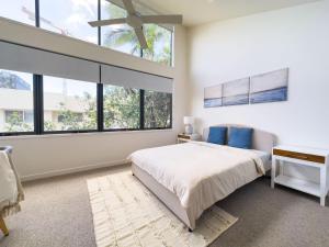 a bedroom with a bed and large windows at Unique Kirra townhouse in Gold Coast