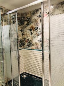 La salle de bains est pourvue d'une douche et d'un papier peint floral. dans l'établissement المنيل -شقة مفروشة للإيجار 5 نجوم - بارقي احياء القاهرة -, au Caire