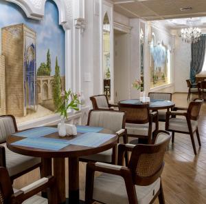 a restaurant with tables and chairs and a painting on the wall at Zarafshon Parkside in Samarkand