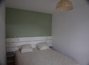 un letto con due cuscini in una camera da letto di Appt Perros Guirec sur plage Trestraou et côte granit rose a Perros-Guirec