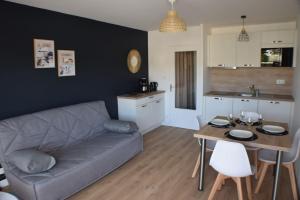 a living room with a couch and a table at Appt Perros Guirec sur plage Trestraou et côte granit rose in Perros-Guirec