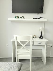 a white desk with a lamp and a tv on a wall at Oaza apartmani 3 in Senta