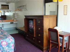 Habitación con escritorio, TV y mesa con silla. en Gray Plaza Motel, en Benton